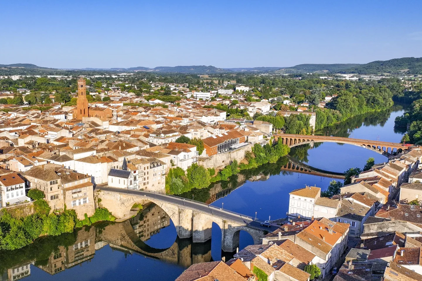 Vue aérienne de la cathédrale Saint-Étienne de Cahors, un édifice historique en pierre avec des dômes et des clochers distinctifs, entouré de toits en tuiles rouges dans le centre-ville.